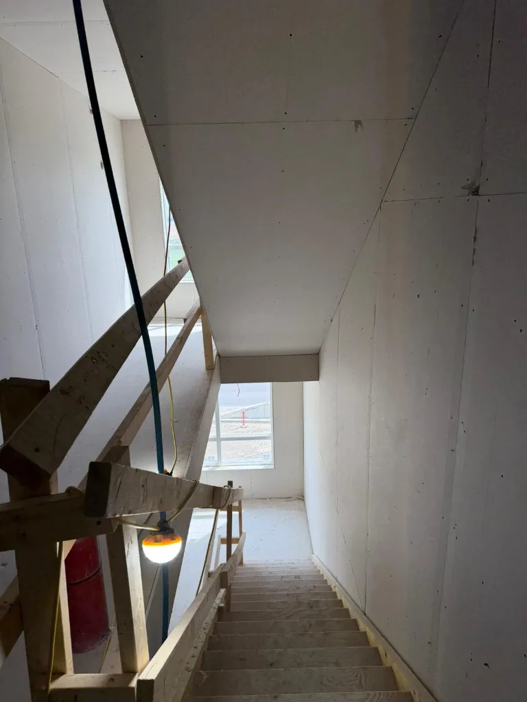 High-angle view of stud framing with pot lights and vapor barrier